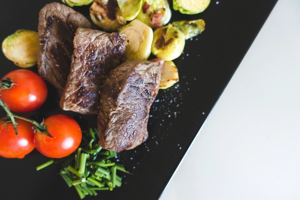 Carne cortada con tomates en plato negro